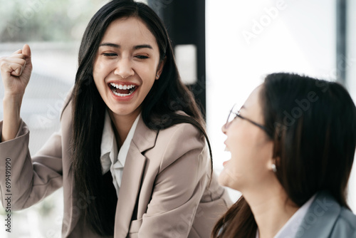 Successful business team, excited young wiman Keeping up arms and showing positive emotions, happy working in modern office on computer. photo