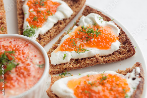 Appetizer with red caviar, sour cream, dill, onion and rye bread on the white table - the finnish recipe for a holiday food, flat lay in minimalistic style photo