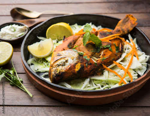 Tandoori Pomfret fish cooked in a clay oven and garnished with lemon , mint, cabbage and carrot salad photo