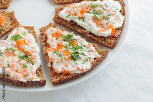 Appetizer with red caviar, sour cream, dill, onion and rye bread on the white table - the finnish recipe for a holiday food in minimalistic style photo