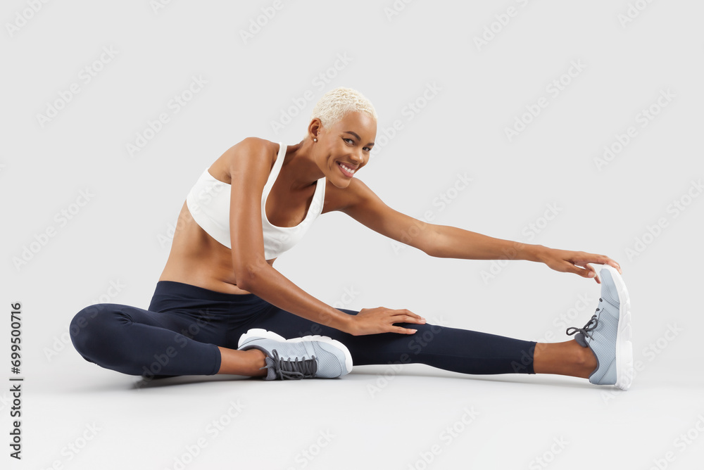 Fototapeta premium Fitness workout, woman stretching arms, legs and back, african latin american female athlete in sportswear, Sportswoman do training physical exercise in gym improve health, isolated on grey background