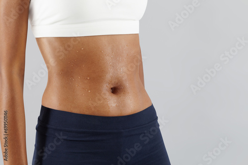 Fitness workout, woman sweaty abdomen, drops of sweat on skin belly Close up, African latin American female athlete in sportswear, Sportswoman do exercise in gym to improve abdominals, health and diet photo