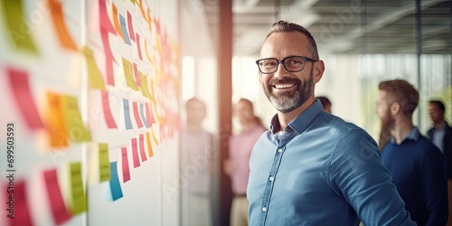 Portrait of creative caucasian happy man in casual wear talking and meeting with presentation Team discussing with colorful note paper on glass white office with sunrise lighting bokeh photo