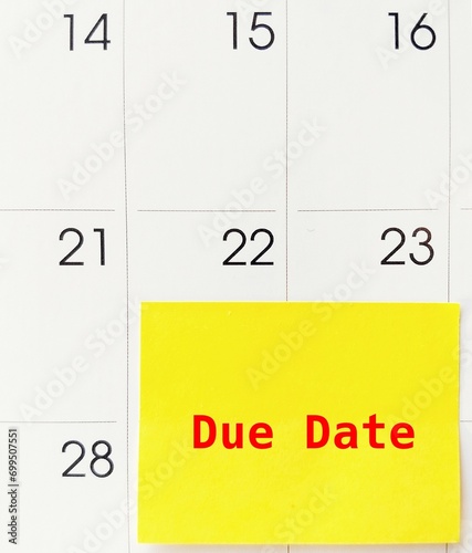 Calendar with yellow stick note DUE DATE - the date on which a woman's baby is expected to be born - date which something has to be done or paid