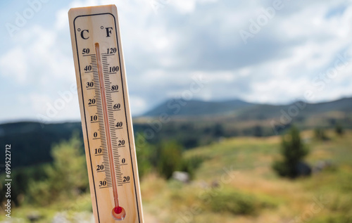 Wooden thermometer with red measuring liquid on a mountain background 