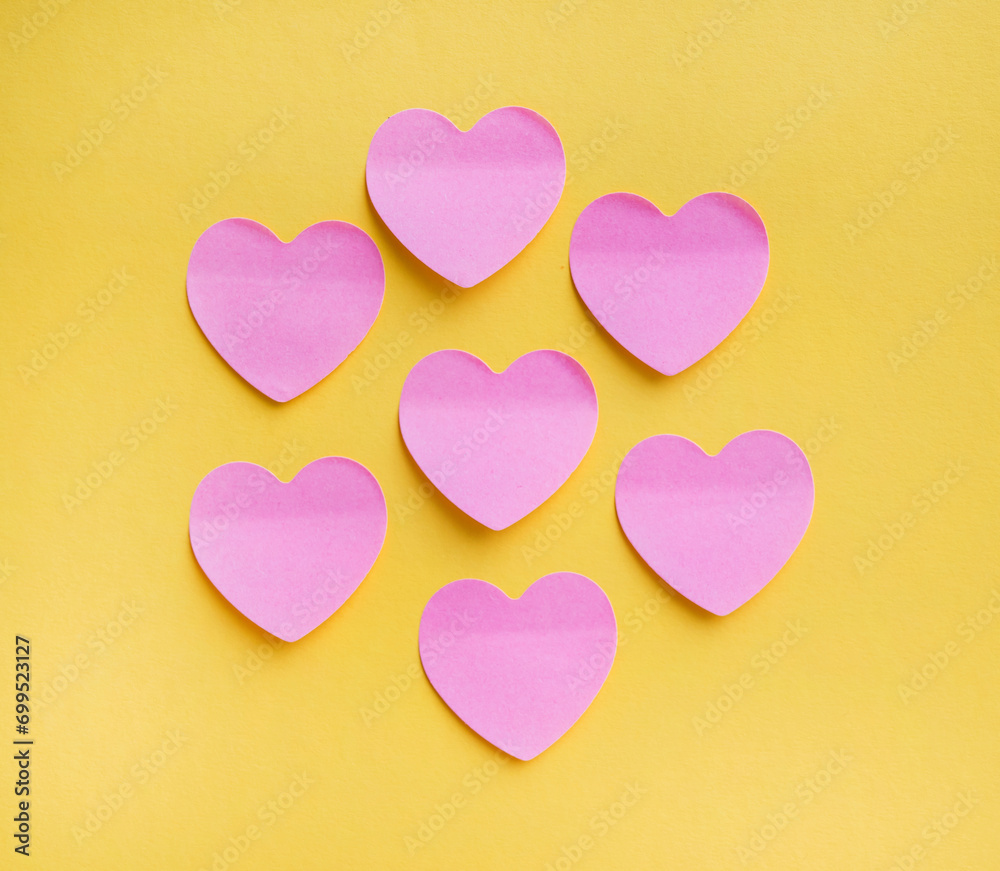 Pink sticky notes in heart shape on yellow background
