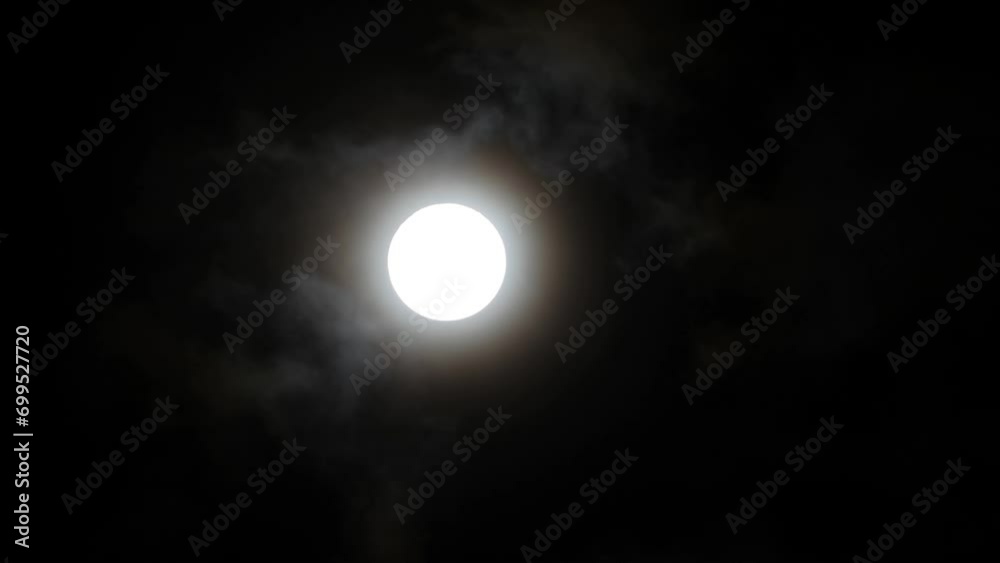 Full moon with moving black clouds. Clouds floating through the bright disk of the moon. Mysterious night scene Full moon with moving black clouds. Clouds floating through the bright disk of the moon. Mysterious night scene