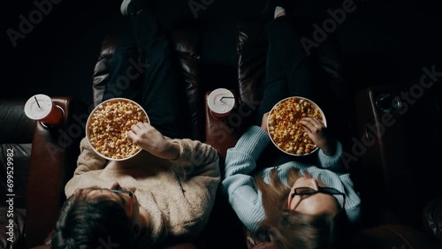 Couple in love A guy and a girl eat popcorn and watch a movie in a cinema using 3D glasses. Concept of a movie show in a cinema