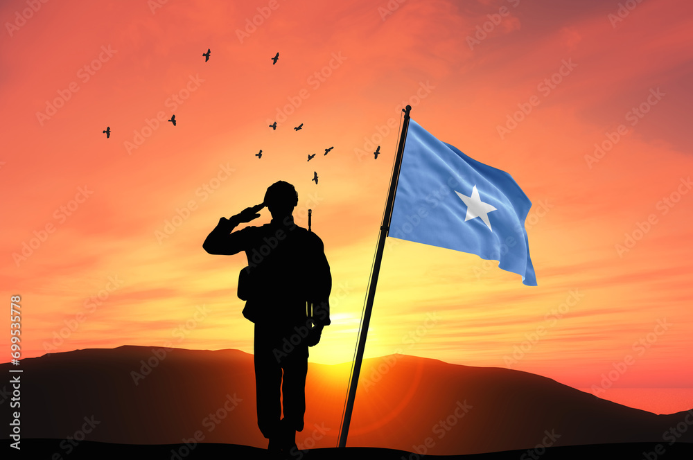 Silhouette of a soldier with the Somalia flag stands against the background of a sunset or sunrise. Concept of national holidays. Commemoration Day.