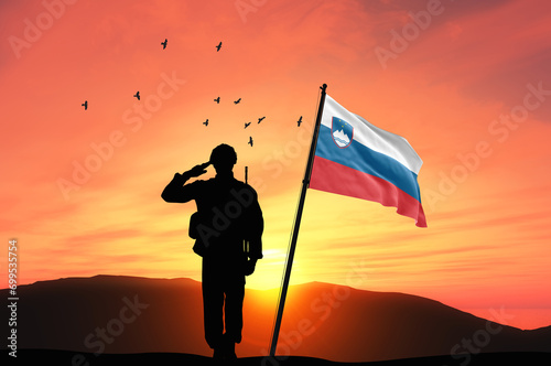 Silhouette of a soldier with the Slovenia flag stands against the background of a sunset or sunrise. Concept of national holidays. Commemoration Day. photo