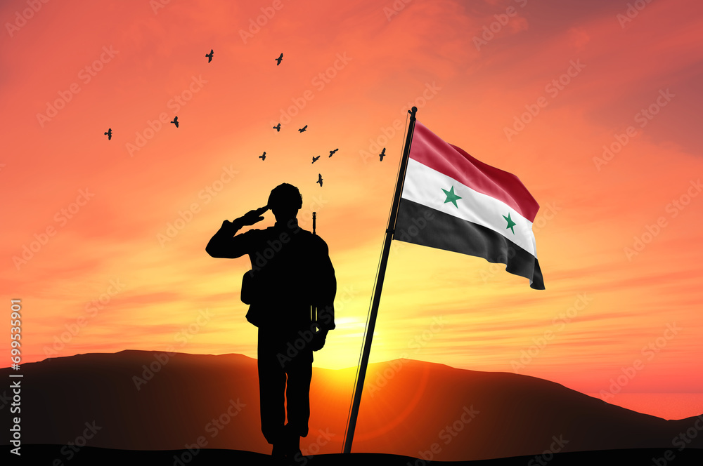 Silhouette of a soldier with the Syria flag stands against the background of a sunset or sunrise. Concept of national holidays. Commemoration Day.