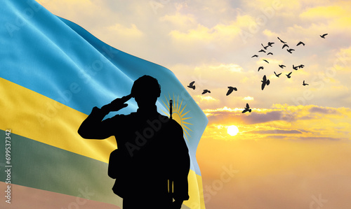 Silhouette of a soldier with the Rwanda flag stands against the background of a sunset or sunrise. Concept of national holidays. Commemoration Day. photo
