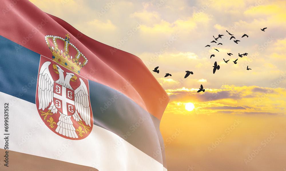 Waving flag of Serbia against the background of a sunset or sunrise. Serbia flag for Independence Day. The symbol of the state on wavy fabric.