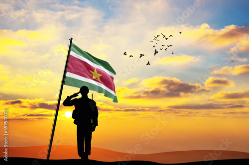 Silhouette of a soldier with the Suriname flag stands against the background of a sunset or sunrise. Concept of national holidays. Commemoration Day.