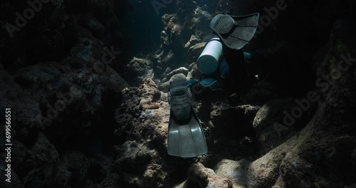 a dark underwater cave getting explored by a scuba diver photo