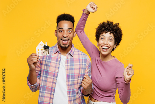 Young winner couple two friends family man woman of African American ethnicity wear purple casual clothes together hold in hand bunch of keys house mockup isolated on plain yellow orange background. photo