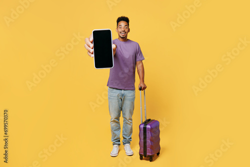 Traveler man wears casual clothes hold bag blank screen mobile cell phone isolated on plain yellow background. Tourist travel abroad in free spare time rest getaway. Air flight trip journey concept. #699570370