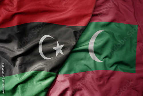 big waving national colorful flag of maldives and national flag of libya .