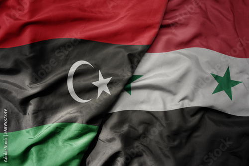 big waving national colorful flag of syria and national flag of libya .