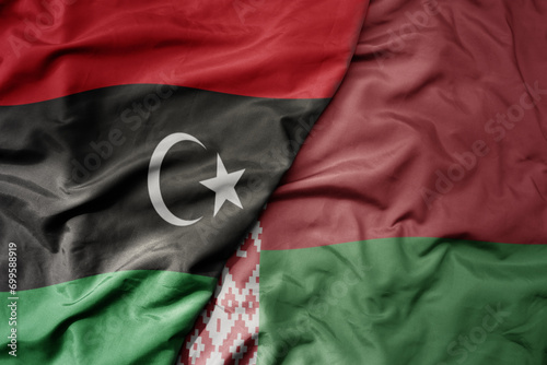 big waving national colorful flag of belarus and national flag of libya .