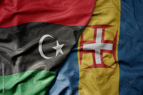 big waving national colorful flag of madeira and national flag of libya .