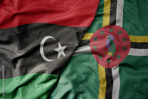 big waving national colorful flag of dominica and national flag of libya .