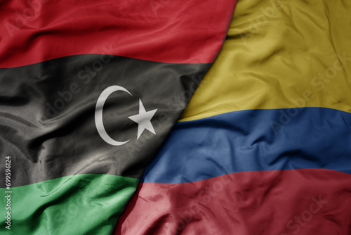big waving national colorful flag of colombia and national flag of libya .