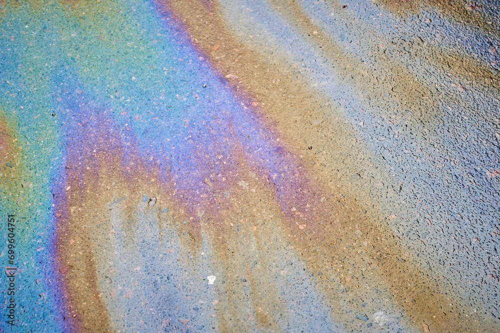 Multi-colored poisonous spots of spilled gasoline on wet pavement during rain. Multi-colored poisonous spots of spilled gasoline on wet pavement during rain.