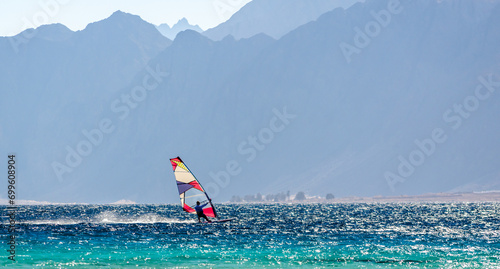 windsurfer rides in the Red Sea against the backdrop of high rocky mountains in Egypt Dahab South Sinai