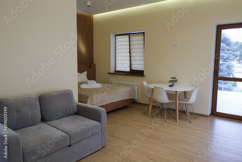 Modern design of a living room in a hotel. Chair  bed  table. Exit to a balcony with a transparent glass door.