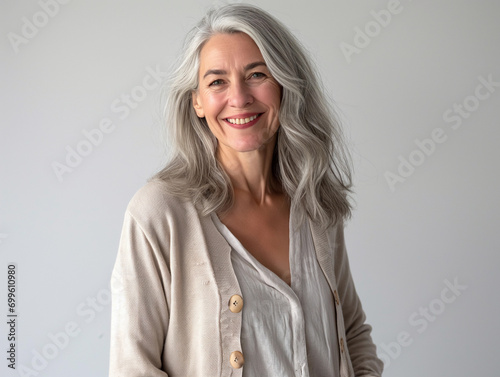Wunderschöne reifere Frau mit langem grauen Haar und beige-farbener Kleidung lächelnd photo