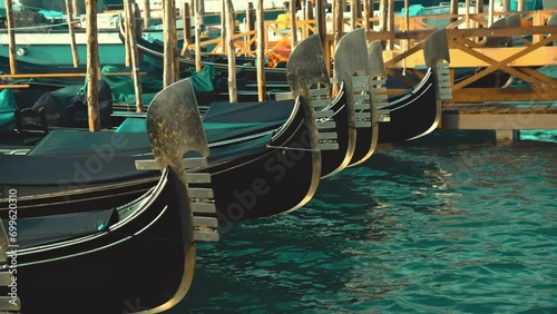 Gondolas with beautifully crafted metal nose ornaments swinging on water in the docks in Venice photo