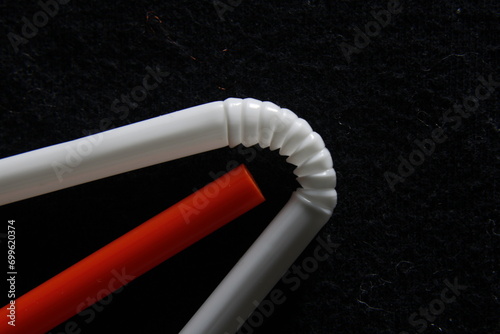 Sorbete de plástico color rojo y blanco  para absorber líquidos, con la curva del espiral con ranuras que lo hace flexible, forma un original diseño abstracto con fondo negro photo
