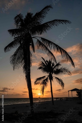 The sun sets over the ocean silhouetting a sailboat on the horizon 