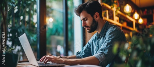 Focused millennial man using laptop, working or studying remotely.