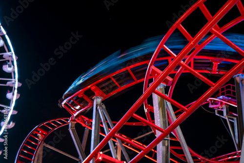 Amusement park at night with close up Ferris wheel and roller coaster captured in motion. family fun on vacation