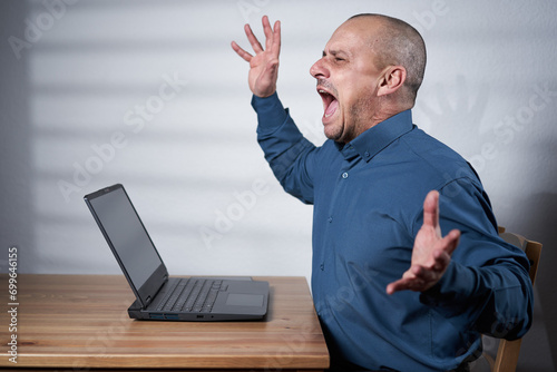 Fotografija Mature businessman with laptop at his desk, shouting
