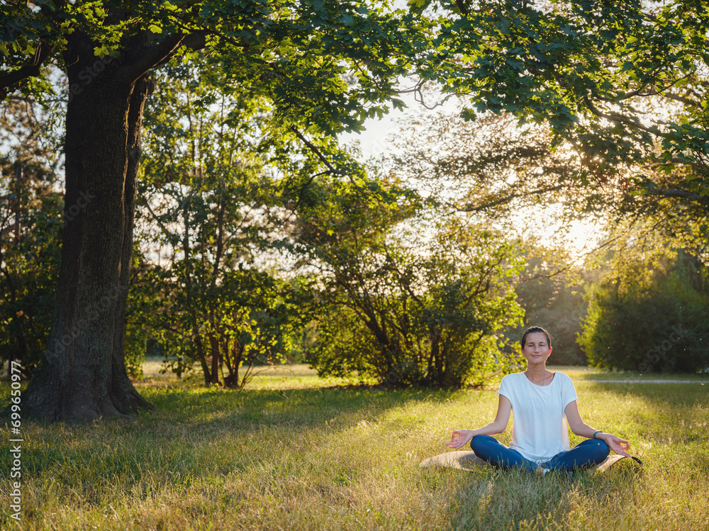 Young asian woman doing meditation in morning or evening at park, healthy woman relaxing and practicing yoga at city park. Mindfulness, destress, Healthy habits and balance concept Young asian woman doing meditation in morning or evening at park, healthy woman relaxing and practicing yoga at city park. Mindfulness, destress, Healthy habits and balance concept