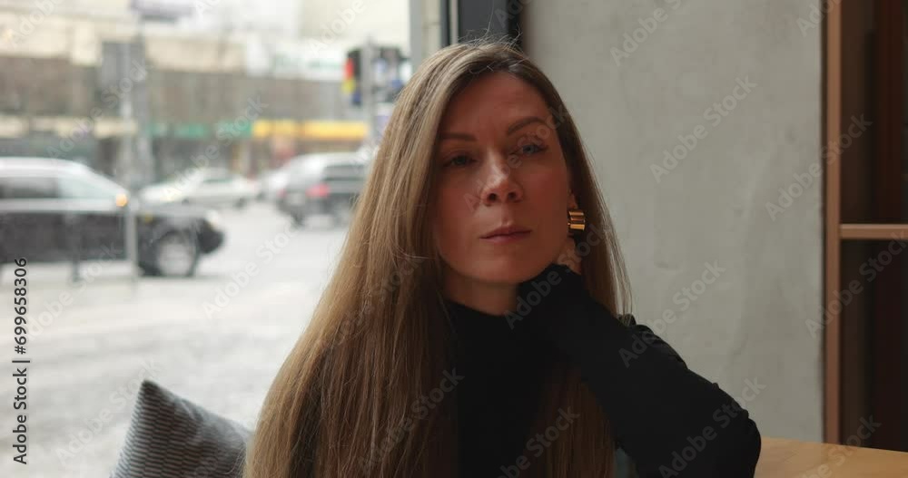 Sad lonely beautiful mid age woman sits with distant look alone in urban cafe. Young woman with long brown hair sitting at table by window facing busy city street. 4k footage. Sad lonely beautiful mid age woman sits with distant look alone in urban cafe. Young woman with long brown hair sitting at table by window facing busy city street. 4k footage.