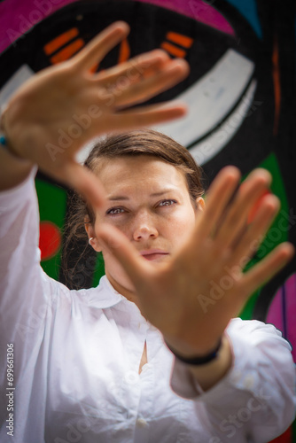 Portrait of a young woman with her face and her hands in front of a colorful painted background