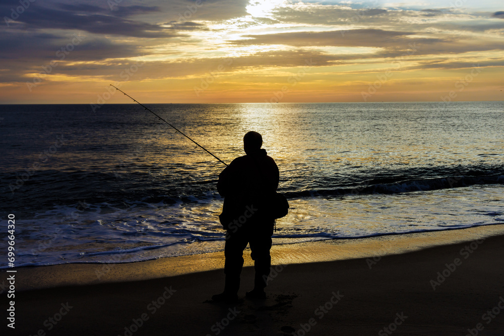 Fisherman catching fish at ocean in morning at sunrise