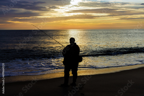 Fisherman catching fish at ocean in morning at sunrise