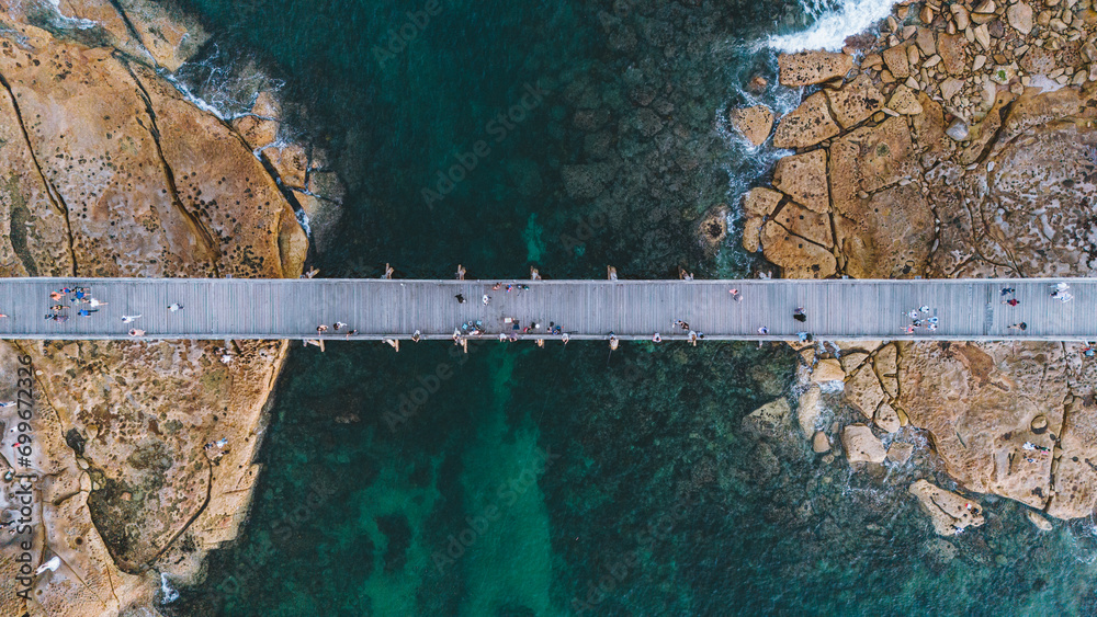Fototapeta premium aerial aerial view from a drone of a pedestrian bridge that connects an island while people walk on it.