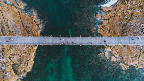 Fototapeta Naklejka Na Ścianę i Meble -  aerial aerial view from a drone of a pedestrian bridge that connects an island while people walk on it.