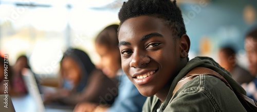 Smiling Black teenager in computer class with laptop, looking at camera.