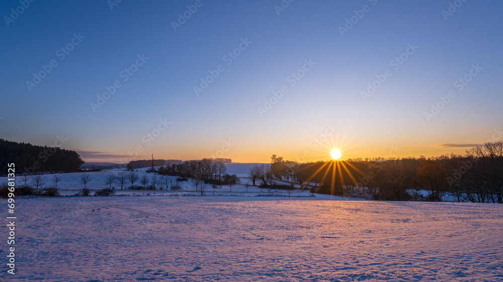 Sonnenuntergang über einem schneebedektem Feld
