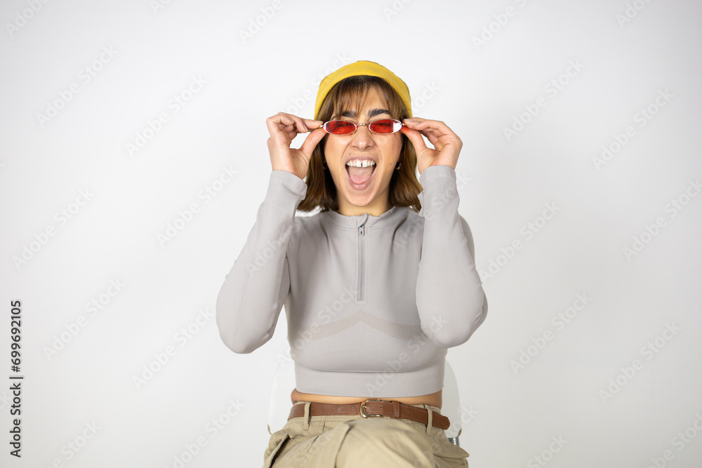 Portrait of a Hispanic woman in studio with red sunglasses and a yellow hat. Portrait of a Hispanic woman in studio with red sunglasses and a yellow hat.