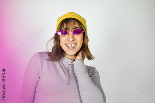 Portrait of a Hispanic woman in studio with lilac sunglasses and a yellow hat.
