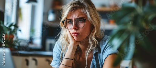 Blonde woman studying at home with a disgusted face.