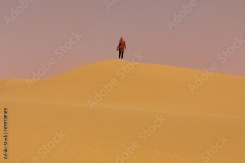 A lone woman in the distance atop a sand dune in the Namib desert in Namibia.